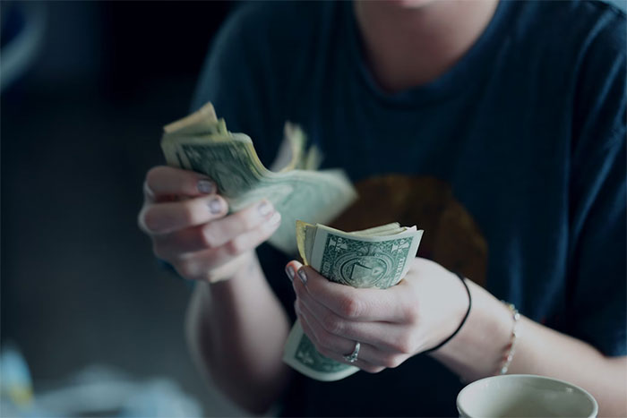 Person counting dollar bills, related to trading services and money demands.