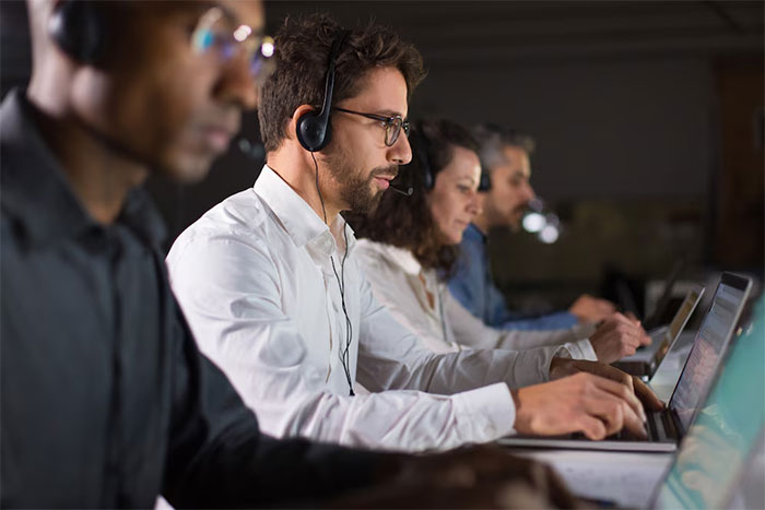 Support team handling ticket escalation requests in a call center environment, with agents focused on their computers.