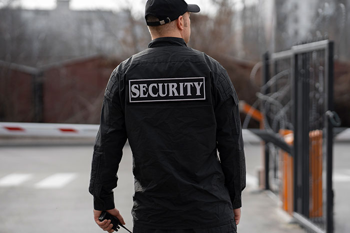Security worker standing by a gate, in compliance with rules.