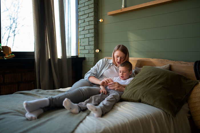 Woman and her 11-year-old son sitting on bed in bedroom, highlighting concerns about open door monitoring and relationship future.